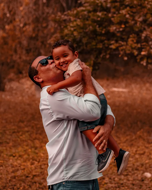 Homem segurando uma criança sorridente e beijando seu rosto