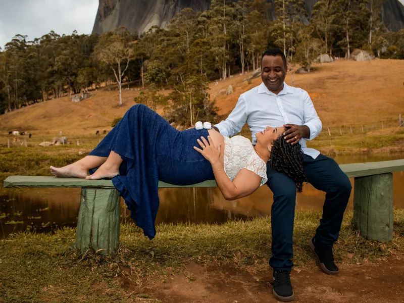 Casal em ensaio de gestante, junto a um lago e às montanhas