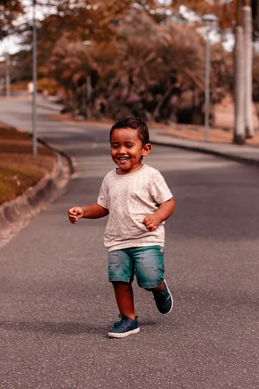 Criança sorrindo enquanto corre em um caminho ao ar livre