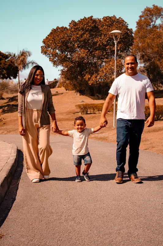 Casal caminhando de mãos dadas com uma criança